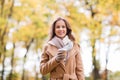 Happy young woman drinking coffee in autumn park Royalty Free Stock Photo