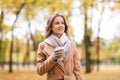 Happy young woman drinking coffee in autumn park Royalty Free Stock Photo