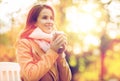 Happy young woman drinking coffee in autumn park Royalty Free Stock Photo