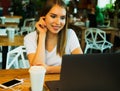 Happy young woman drinking coffee/tea and using laptop in a cof Royalty Free Stock Photo