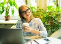 Happy young woman drinking coffee/tea and using laptop in a cof Royalty Free Stock Photo