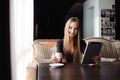 Happy young woman drinking coffee tea and using tablet computer in a coffee shop. Royalty Free Stock Photo