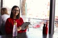 Happy young woman drinking lemonade / iced tea and using tablet computer in a coffee shop Royalty Free Stock Photo