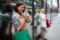 Happy young woman drinking take away coffee and walking with bags after shopping in city. Royalty Free Stock Photo