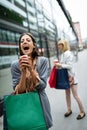 Happy young woman drinking take away coffee and walking with bags after shopping in city. Royalty Free Stock Photo