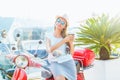 Happy young woman drinking takeaway coffee near her red moped in Royalty Free Stock Photo