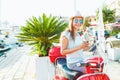 Happy young woman drinking takeaway coffee near her red moped in Royalty Free Stock Photo