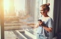 Happy young woman drinks coffee in morning at window Royalty Free Stock Photo