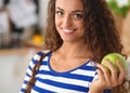 Happy young woman eating apples on kitchen