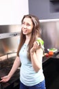 Happy young woman eating apples on kitchen
