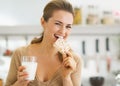 Happy young woman eating crisp bread with milk in kitchen Royalty Free Stock Photo