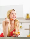 Happy young woman eating fresh fruits salad in kitchen Royalty Free Stock Photo