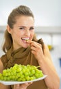 Happy young woman eating grape