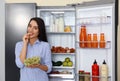 Happy young woman eating grape near refrigerator Royalty Free Stock Photo