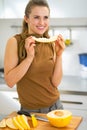 Happy young woman eating melon in kitchen