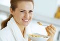 Happy young woman eating muesli in kitchen Royalty Free Stock Photo