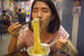 Happy young woman eating noodle soup with dumpling in Chinese restaurant. Japanese girl using chopsticks eating Chinese