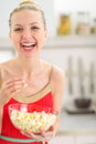 Happy young woman eating popcorn in kitchen Royalty Free Stock Photo