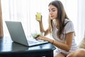 Happy young woman eating salad from a bowl and drinking orange juice while watching movie on laptop Royalty Free Stock Photo