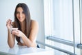 Happy young woman eating yogurt in kitchen Royalty Free Stock Photo