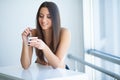 Happy young woman eating yogurt in kitchen Royalty Free Stock Photo