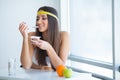 Happy young woman eating yogurt in kitchen Royalty Free Stock Photo