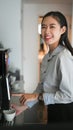 Happy young woman employee smiling and making coffee with coffee machine during break in office. Royalty Free Stock Photo
