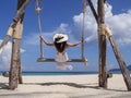 Happy young woman enjoy and sway the wooden swing over the sea beach, blue sky and cloud. Tourist women relax and enjoy with wood Royalty Free Stock Photo