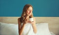 Happy young woman enjoying with cup of hot coffee sitting on the bed in the morning Royalty Free Stock Photo