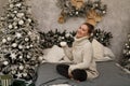 Happy young woman enjoying drinking tea or coffee in living room with Christmas decor over new year tree background Royalty Free Stock Photo