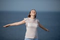 Woman relaxing at beach enjoying summer freedom with open arms and hair in the wind by the water seaside.