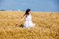 Happy young woman enjoying life in golden wheat field