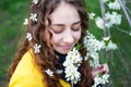 Happy young woman enjoying smell flowers over spring garden background Royalty Free Stock Photo