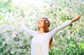 Happy young woman enjoying spring time over flowering garden