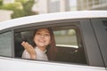 Happy young woman enjoying the views on a road trip while looking through the car window, saying hello waving her hand Royalty Free Stock Photo