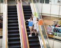 Happy young woman on escalator in shopping mall Royalty Free Stock Photo