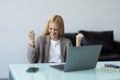 Happy young woman excited with great news, win, success, luck. Woman looking at laptop screen making winner gesture, shouting fir Royalty Free Stock Photo