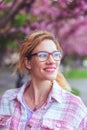 Happy young woman in eyeglasses looking away in park at springtime Royalty Free Stock Photo