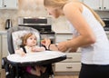 Happy young woman feeding cute little girl with a spoon. Royalty Free Stock Photo