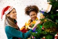 Happy young woman and friends decorating and preparation ornament on Christmas tree with enjoy together. Royalty Free Stock Photo