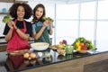 Happy young woman friends different races make salad together and showing vegetables