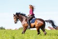 Happy young woman galloping horseback on field