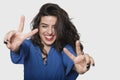 Happy young woman gesturing victory sign against gray background Royalty Free Stock Photo