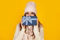 Happy young woman with a gift box in her hands, covers half of her face with a New Year's gift. The girl shows a gift to the Royalty Free Stock Photo