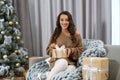 Happy young woman with gift near Christmas tree at home Royalty Free Stock Photo