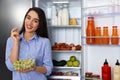 Happy young woman with grape near open refrigerator Royalty Free Stock Photo