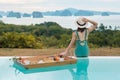 Happy young woman in green swimsuit having Floating Breakfast tray in luxury pool hotel, girl with hat enjoy in tropical resort. Royalty Free Stock Photo