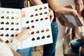 Happy young woman with hairdresser choosing hair color from palette samples at salon