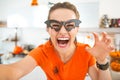 Happy young woman in Halloween decorated kitchen taking selfie