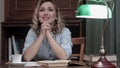 Happy young woman with hands clasped praying while sitting at desk in her home office Royalty Free Stock Photo